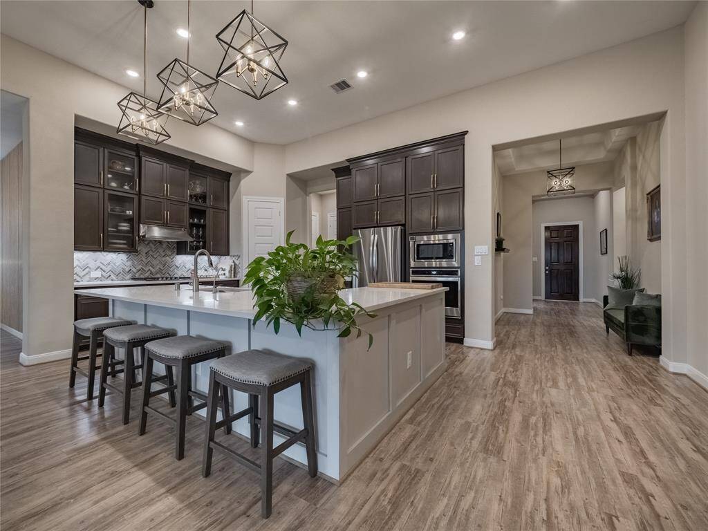 from the small hallway you enter the open floor plan of this fabulous well maintained home  with the beautiful flooring seamless flow from kitchen to family to dining room. oversized island with since modern lighting granite counter tops stainless steel appliances fridge also stays