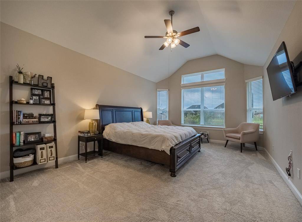 primary bedroom with lots of windows over looking the lake , ceiling fan very spacious has a sitting area
