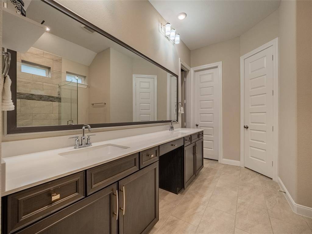 primary bath very spacious large mirror double sinks his and her closets tile flooring