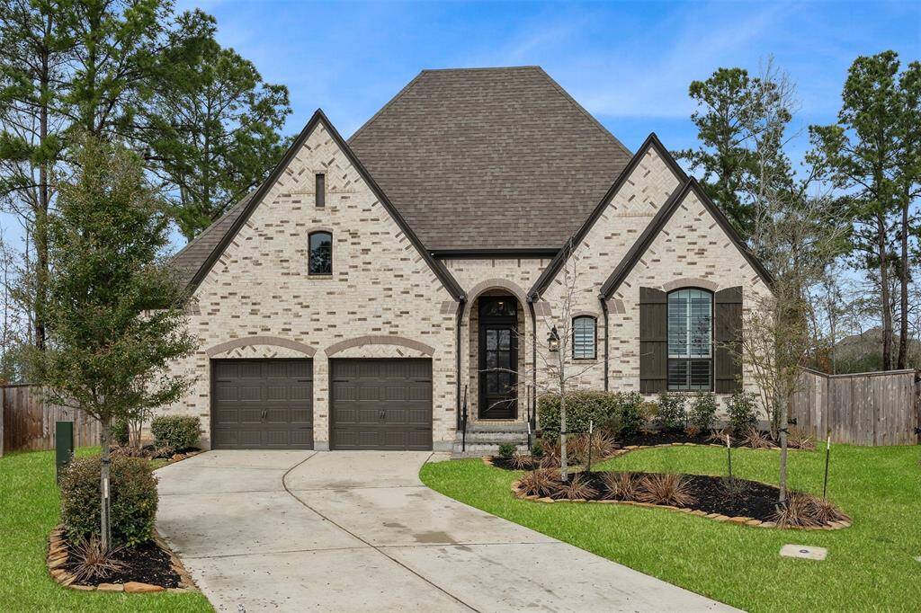 This charming home features a classic brick exterior with a steeply pitched roof and inviting double garage. The well-maintained front yard includes landscaped plantings and mature trees, offering a serene and welcoming appearance.