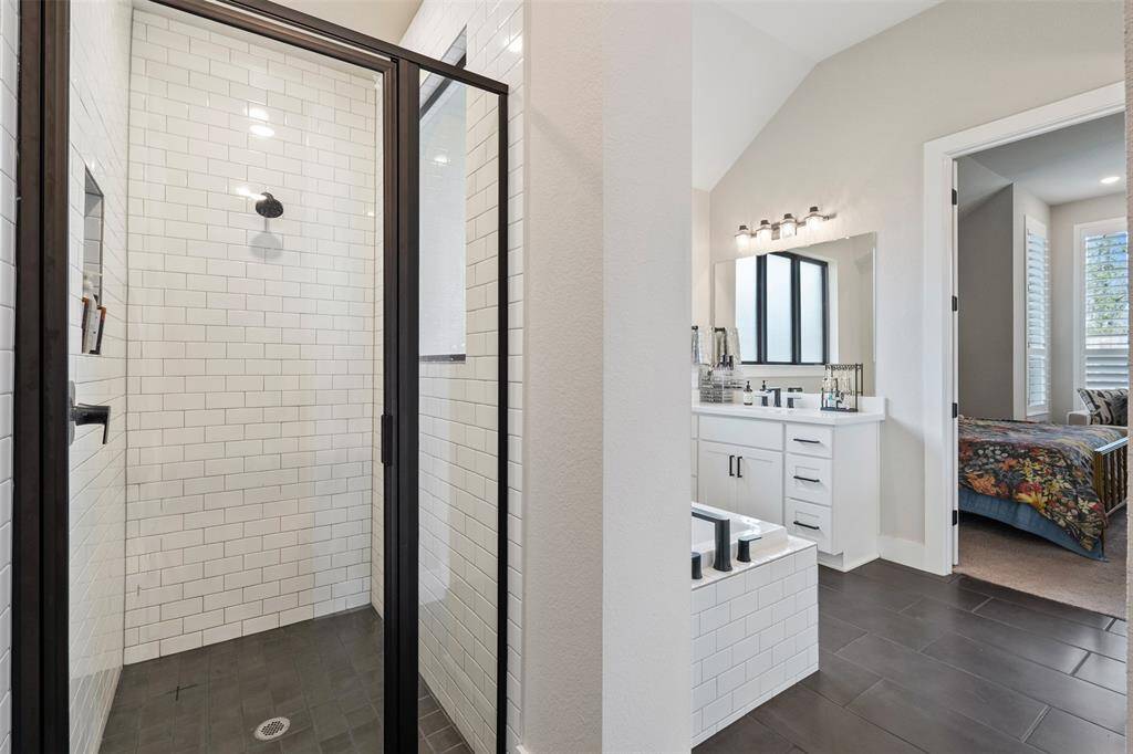 This bathroom shows a sleek glass-enclosed shower featuring white subway tiles and dark fixtures.