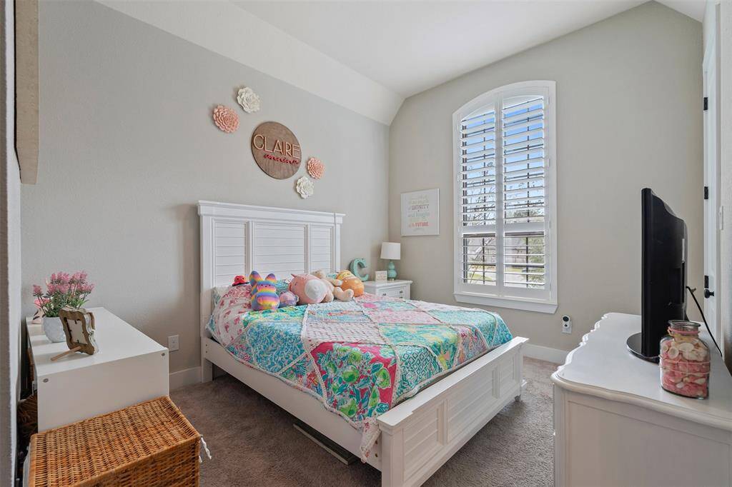 This cozy bedroom a large arched window with shutters.