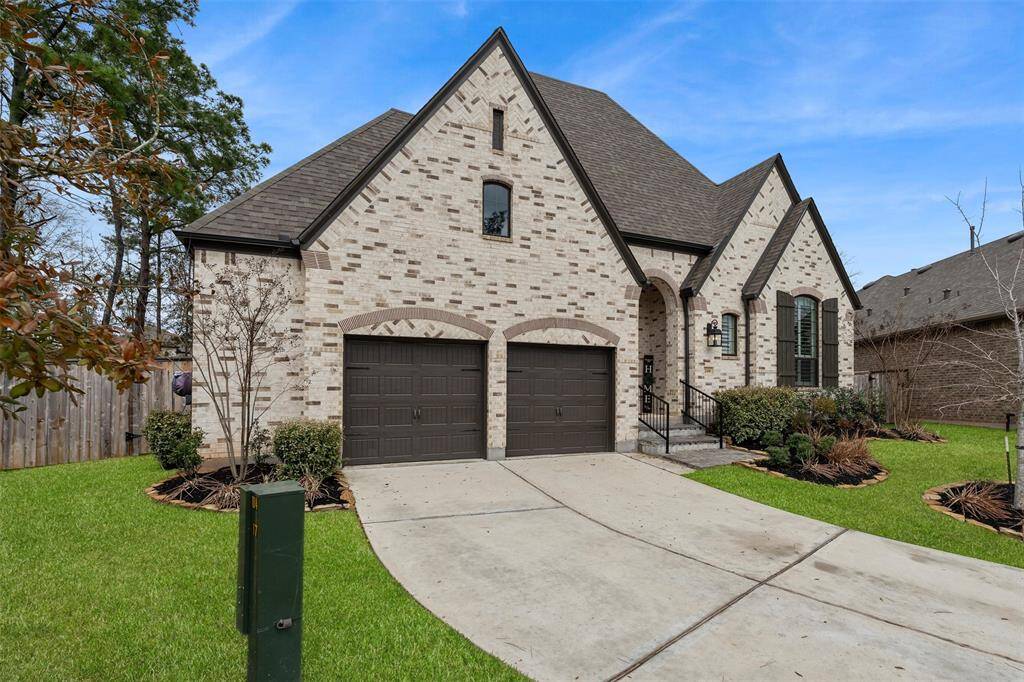 This charming brick home showcases a steeply pitched roof and a two-car garage. The well-maintained lawn and landscaping add to its curb appeal, while the arched entrance and large windows enhance its elegant design.