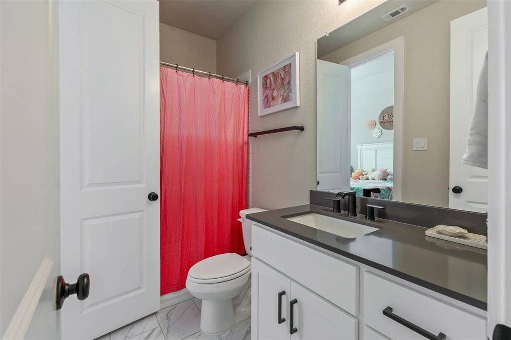 This bathroom features a sleek, dark countertop, white cabinetry, and a single sink.