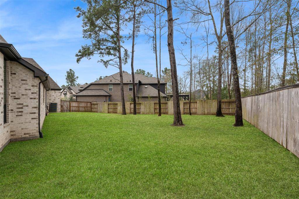 This photo shows a spacious, fenced backyard with a well-maintained lawn, bordered by trees for added privacy. Ideal for outdoor activities and entertaining.