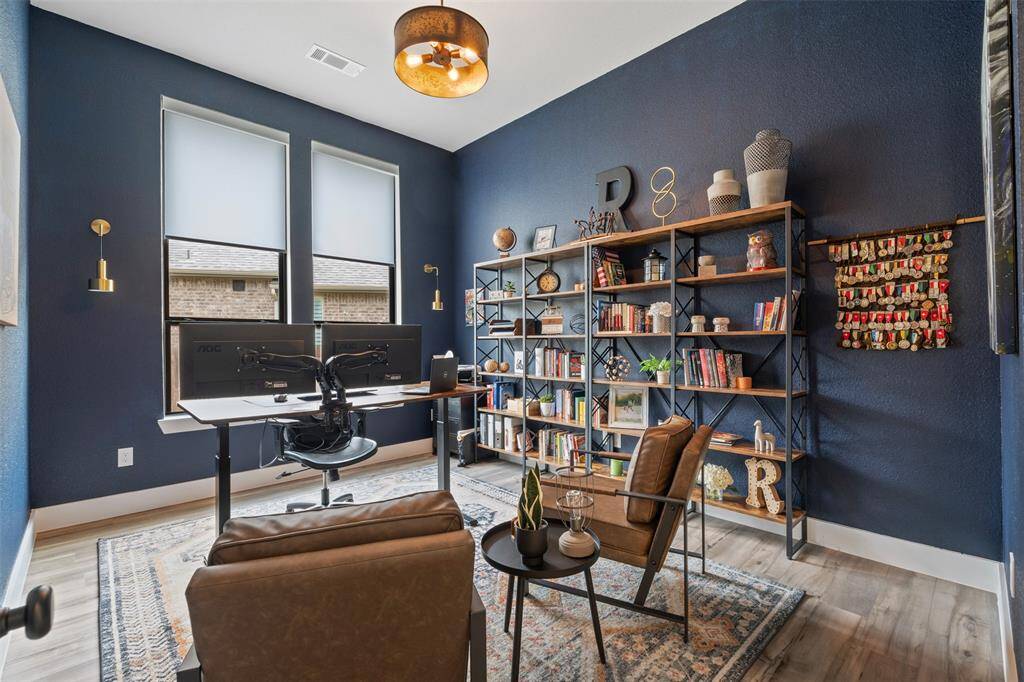 Stylish home office with rich blue walls, featuring a large window for natural light, creating an inviting and productive workspace.