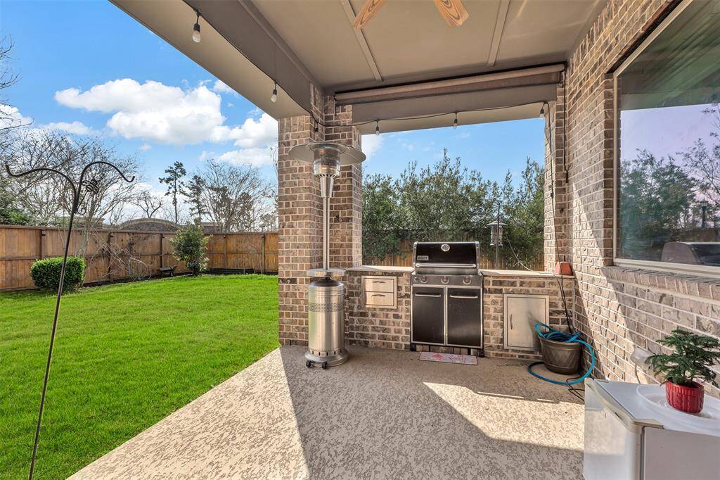 A view of the mini outdoor kitchen and the green space from the covered patio