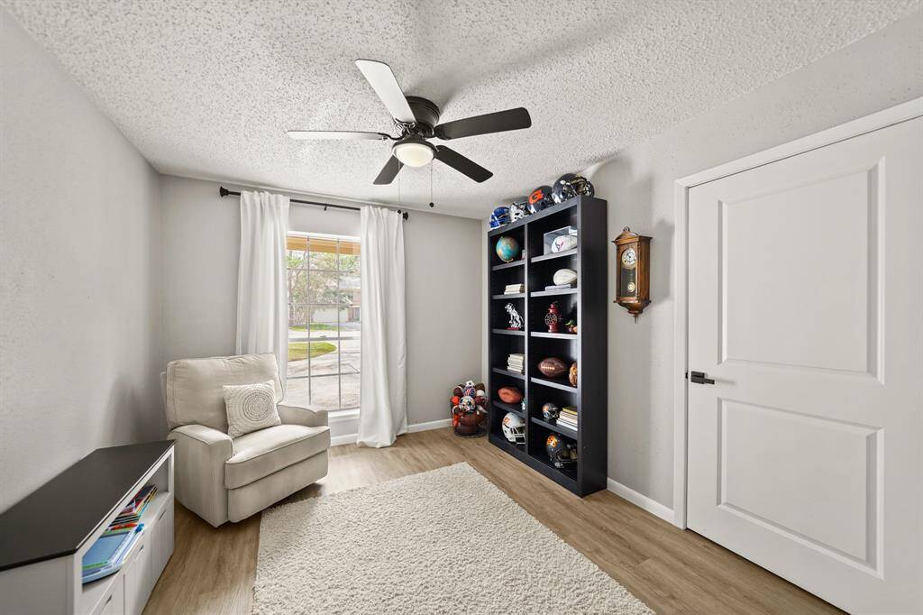 Features include a ceiling fan with lighting, window with drapes overlooking the front yard & vinyl plank hardwood floors. Offering flexibility, there is a door just behind the bookcase offering access to the owner's suite.