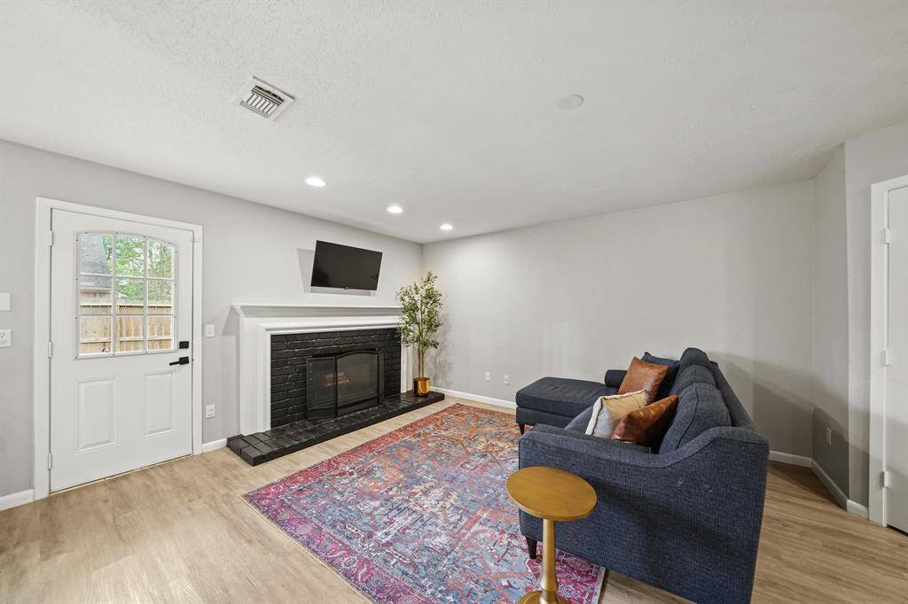A glass door offers access to the backyard and the cozy brick surrounded wood-burning fireplace with custom mantel & bricked hearth includes recessed lighting.