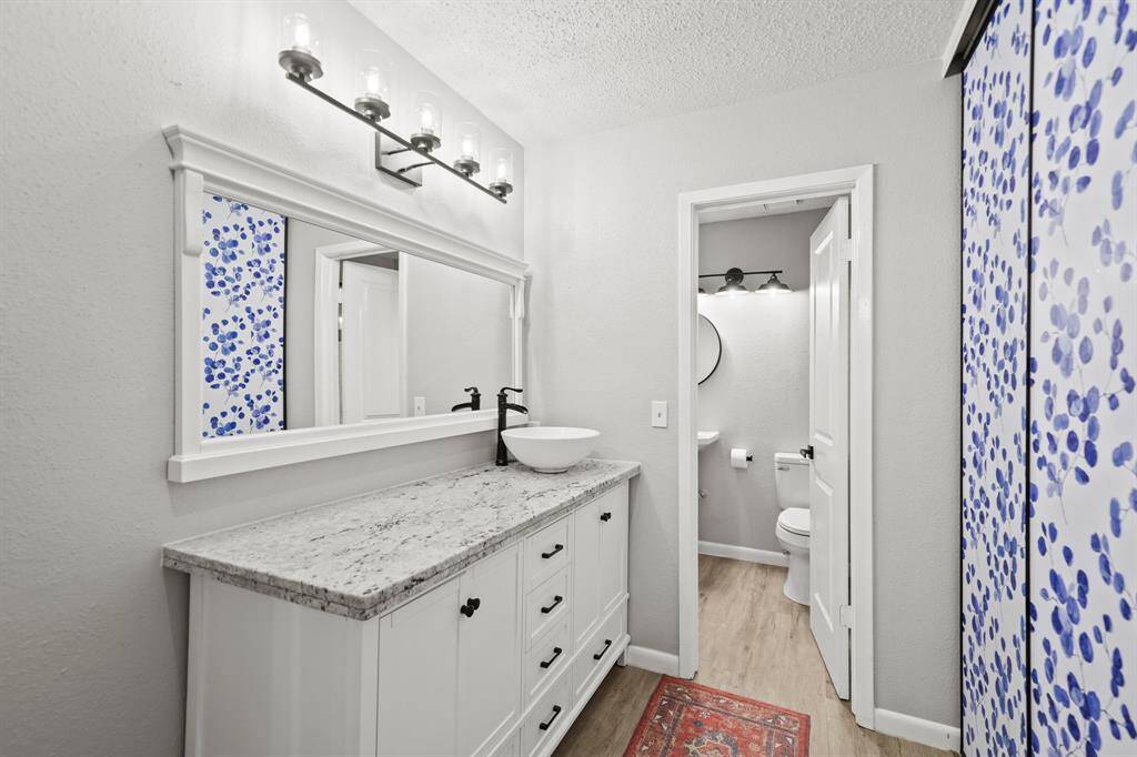 The furniture-like vanity with granite counter top & vessel sink includes a beautiful framed mirror with wall mounted lighting above.