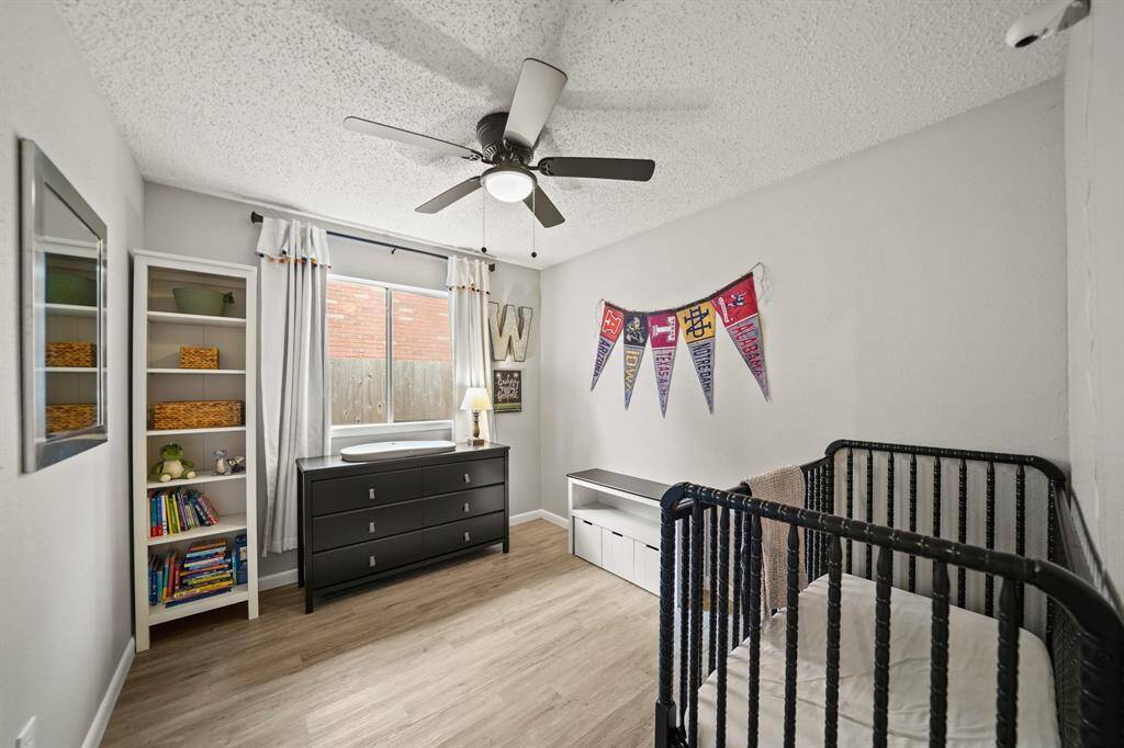 The third bedroom includes a ceiling with light fixture, window with drapes & views of the side yard & luxury vinyl plank hardwood flooring.
