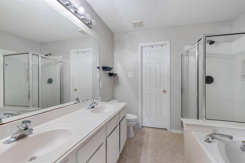 Step into the primary bathroom, featuring dual sinks and elegant tile flooring, creating a spa-like atmosphere.