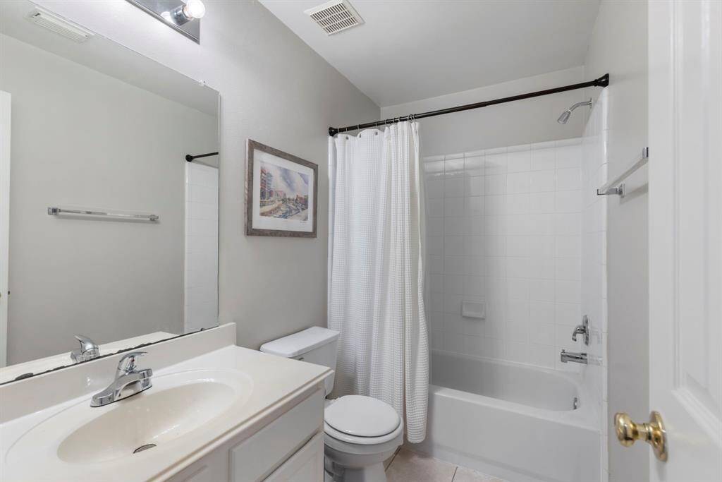 The secondary bathroom boasts tile flooring and a tiled shower/tub combo, offering both style and functionality.