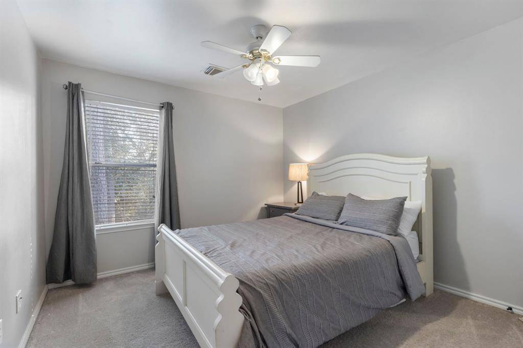 The last secondary bedroom features carpet, neutral paint, a ceiling fan, and a window, creating a bright and comfortable space.