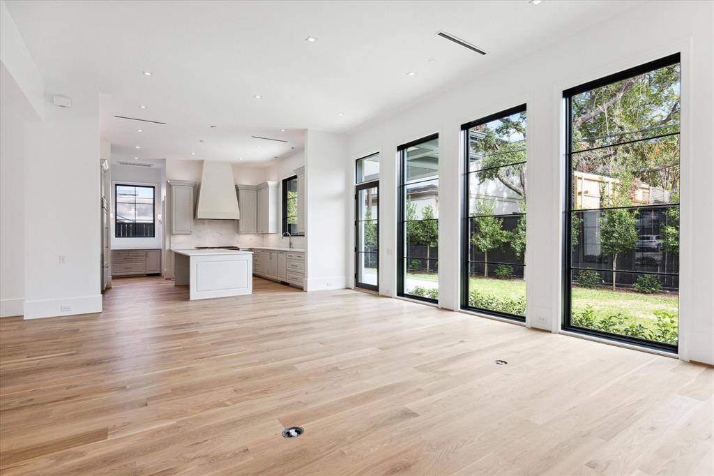 [Kitchen]The living room and open gathering kitchen share views of the loggia, summer kitchen with Coyote grill and sink, and backyard through an aluminum-clad glass door and tall windows.