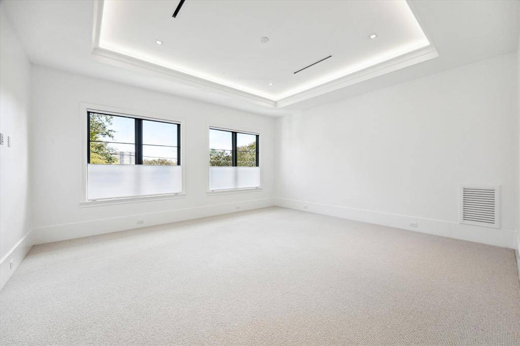 [Primary Bedroom]White oak floors transition to Berber-style wool carpet in the secluded primary suite. Amenities include a 10-ft tray ceiling, cove and recessed lighting, and pre-wiring for a wall-mount television and speakers.