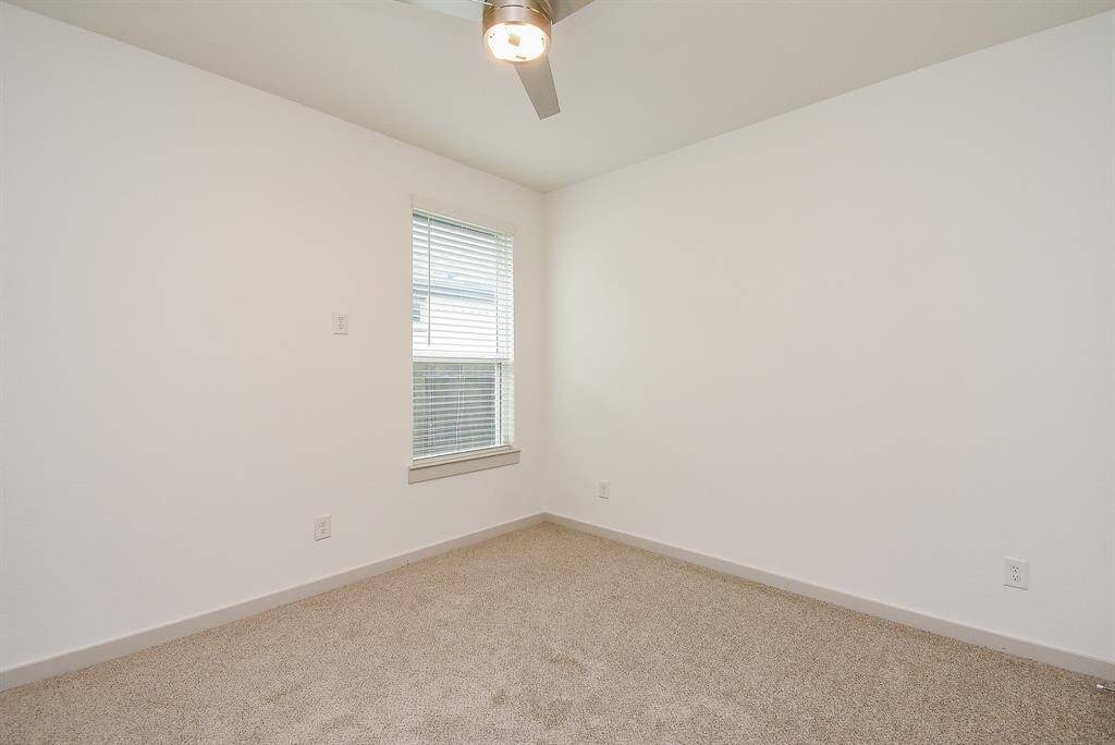 A comfortable carpeted secondary bedroom invites both family members and visiting guests.
