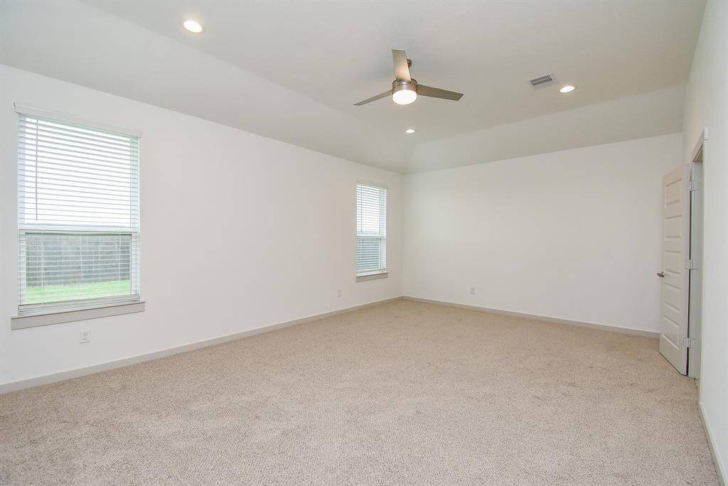 Great natural light is joined by recessed ceiling light and fan fixture in your huge carpeted primary suite.