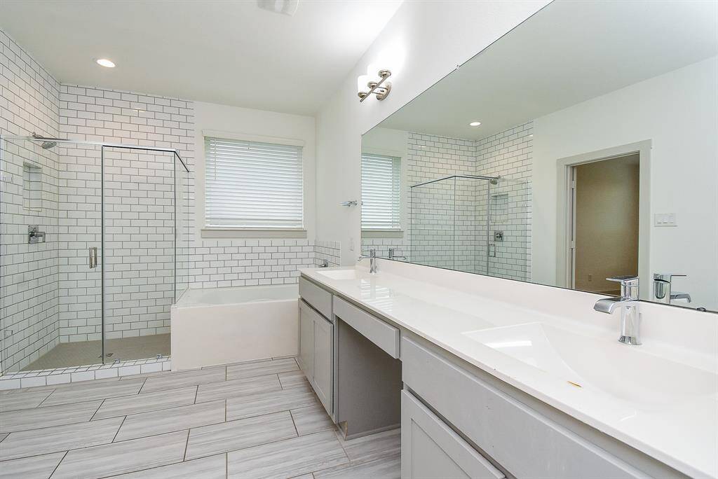There's nothing like a creamy white primary bath to refresh us and make us feel brand new! Dual sinks sit in granite? quartz? other? countertops, under a wall-spanning mirror and contemporary lighting, above, and durable, easy maintenance flooring, below.