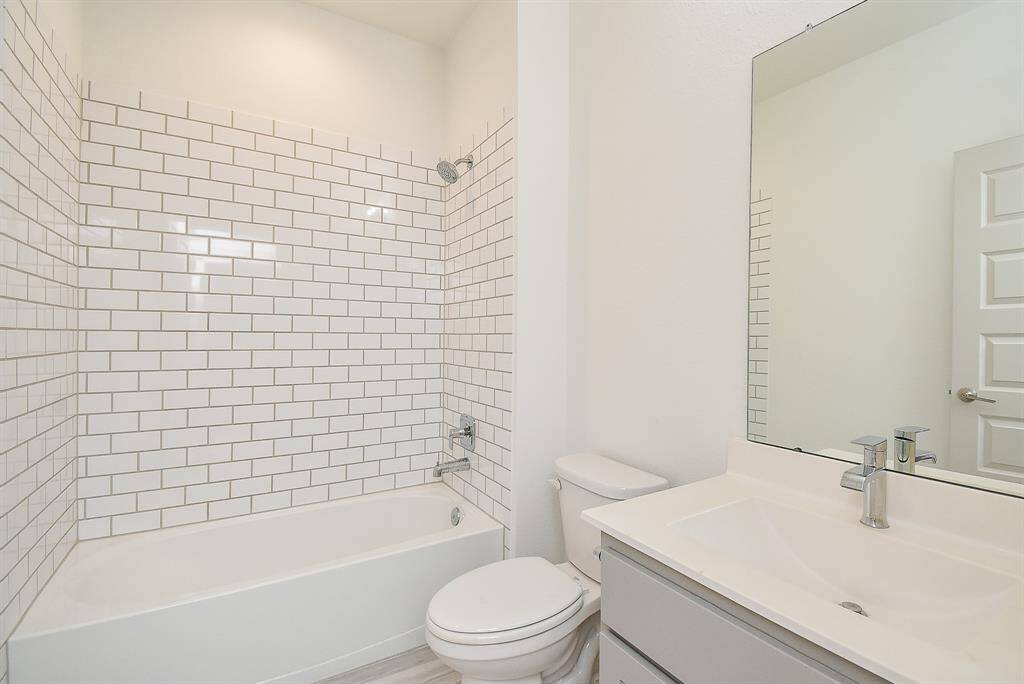 Bright and spotless, this full bathroom is a study in creamy white tile in combined shower/bathtub and standard appointments.