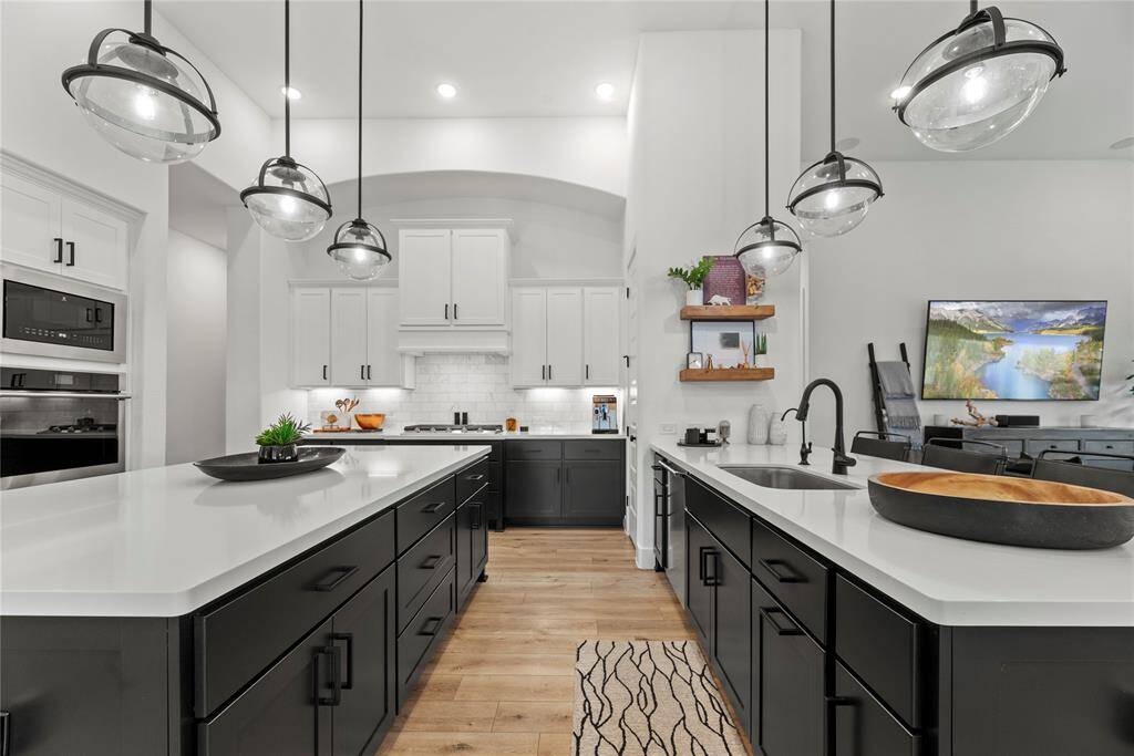 This stunning space offers exquisite quartz countertops complemented by a stylish backsplash, creating a harmonious blend of elegance and functionality. Equipped with top-of-the-line stainless steel appliances, it invites culinary creativity at every turn. The rich cabinets, adorned with modern hardware, exude sophistication, while the pendant lighting, under-cabinet and recessed lighting illuminate the area beautifully, enhancing both ambiance and practicality.