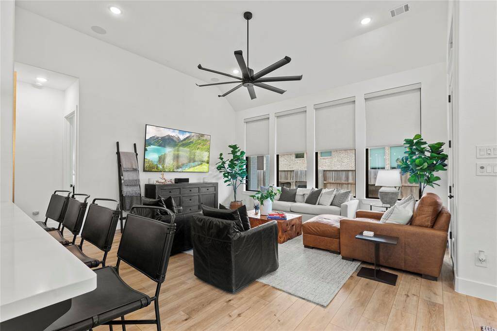 The family room features hardwood floors, modern fixture, backyard access, recessed lighting, and tall ceilings with picturesque views of the backyard.