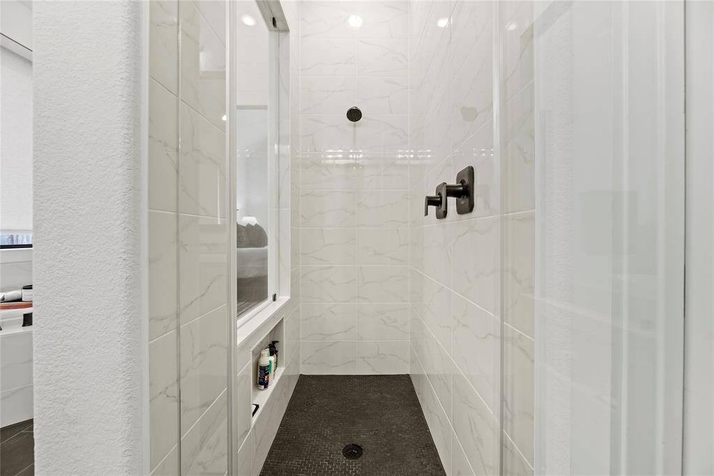 The expansive walk-in shower, adorned with stunning tile work and a sleek glass front, offers a luxurious escape for a quick rinse or a refreshing retreat.