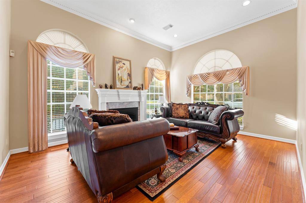 Formal Living with oak flooring, 1 of 2 fireplaces and lots of natural light for beautiful views of the mature trees