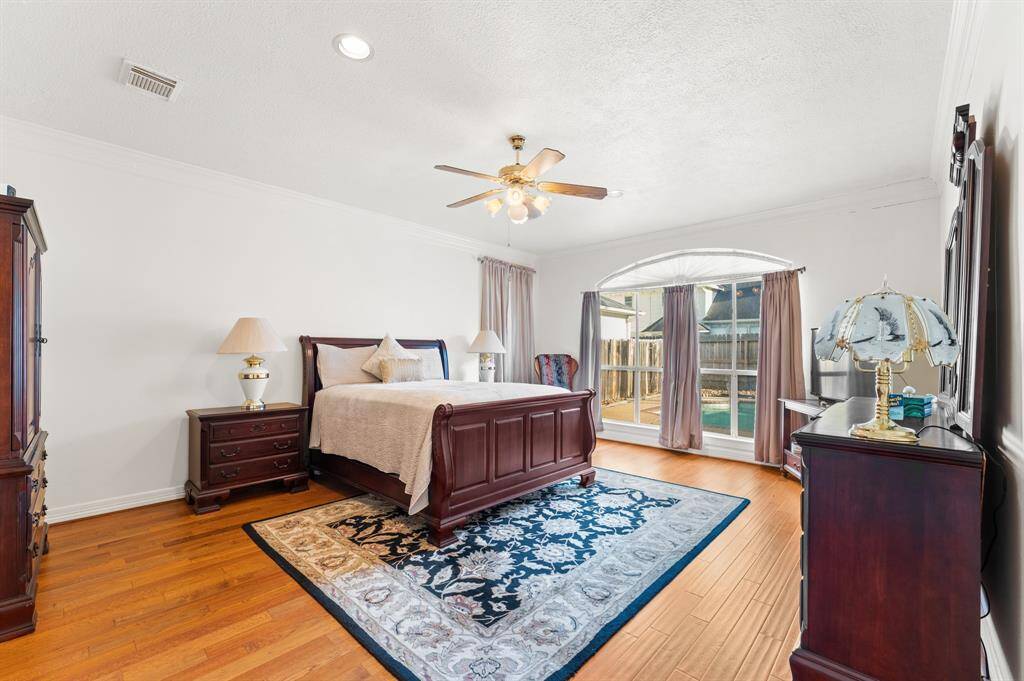 Large master bedroom with lots of large windows and a pool view