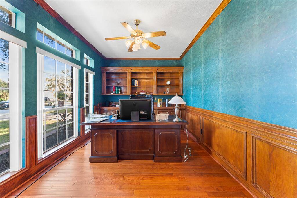 Large office/study with custom built in shelving and plenty of natural lighting and scenic views of mature trees