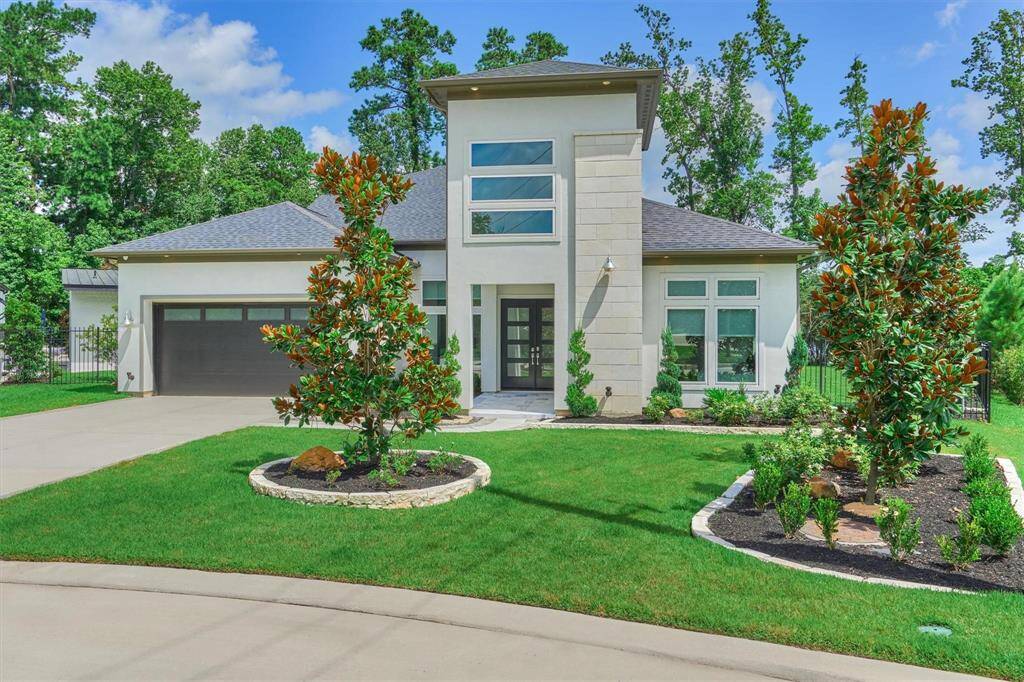 This luxury modern home features a striking two-story entrance with large chandelier and large windows, a sleek façade, and a well-maintained lawn. The drive way offers ample space, and the overall design emphasizes clean lines and contemporary style.