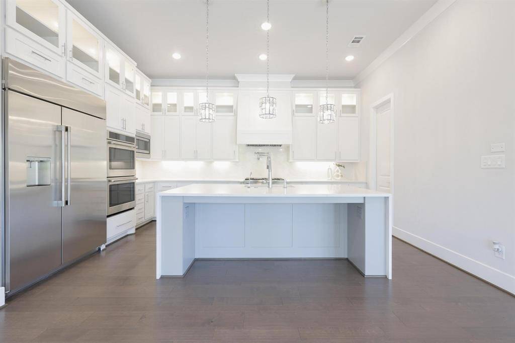 This stunning primary bathroom features a spacious, elegant design with marble flooring and walls, a large soaking tub, a walk-in shower, dual vanities,  additional vanity and ample natural light. The modern fixtures and a chandelier add a touch of luxury.
