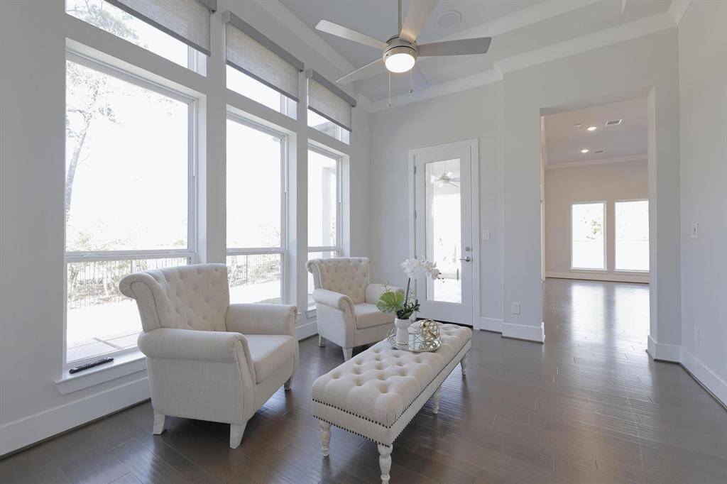 This  guest bedroom  with a modern design neutral color palette, large windows providing ample natural light, and a stylish ceiling fan. The room fits a comfortable queen bed and side table.