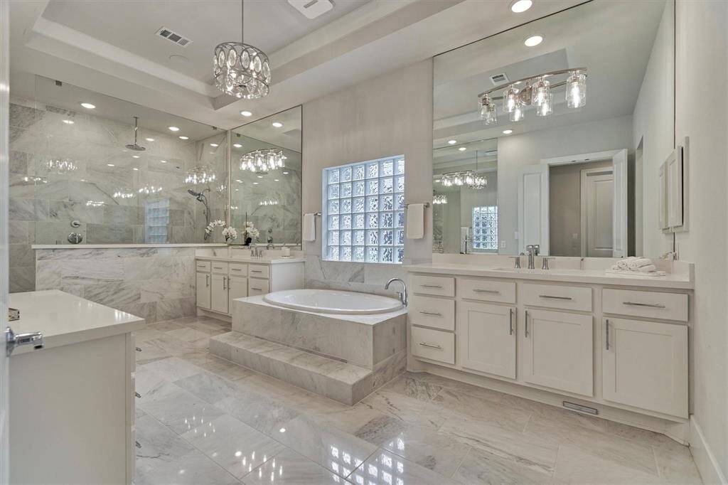 This is a modern, bright guest bathroom featuring a sleek vanity with ample storage, a large mirror, and a spacious glass-enclosed shower with elegant tile work.