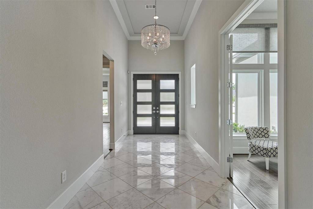 The modern spacious butters with sleek white cabinetry, glass-front upper cabinets, and a large island, features a premium stainless ice maker and wine fridge . The stunning light fixtures and ample counter and space add to its elegance and functionality.
