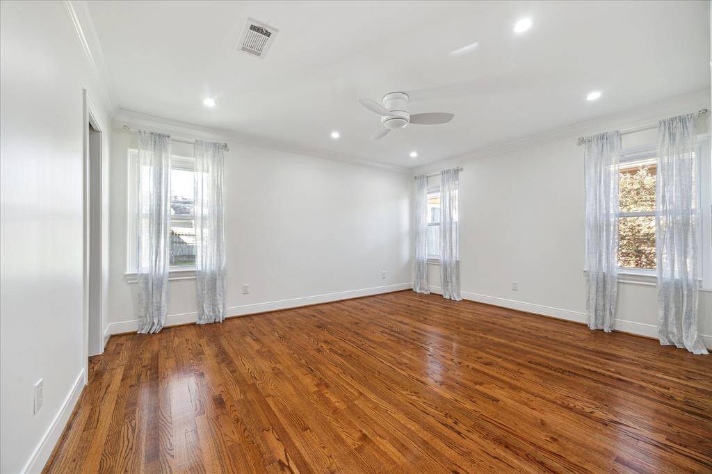 Primary bedroom with plenty of room for a king-sized bed and with two closets: one double door closet and one walk-in. Both closets have custom closet systems with built-in drawers. Custom crown molding, recessed lighting and hard wired for wall mounted TV.