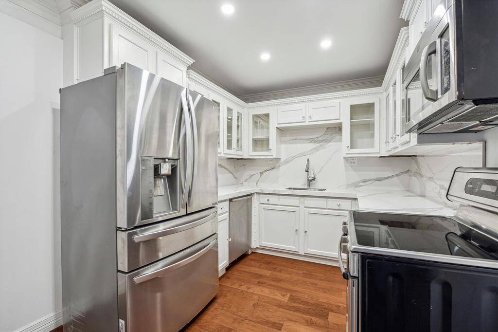 Kitchen with hardwood floors, recessed lighting and crown molding.