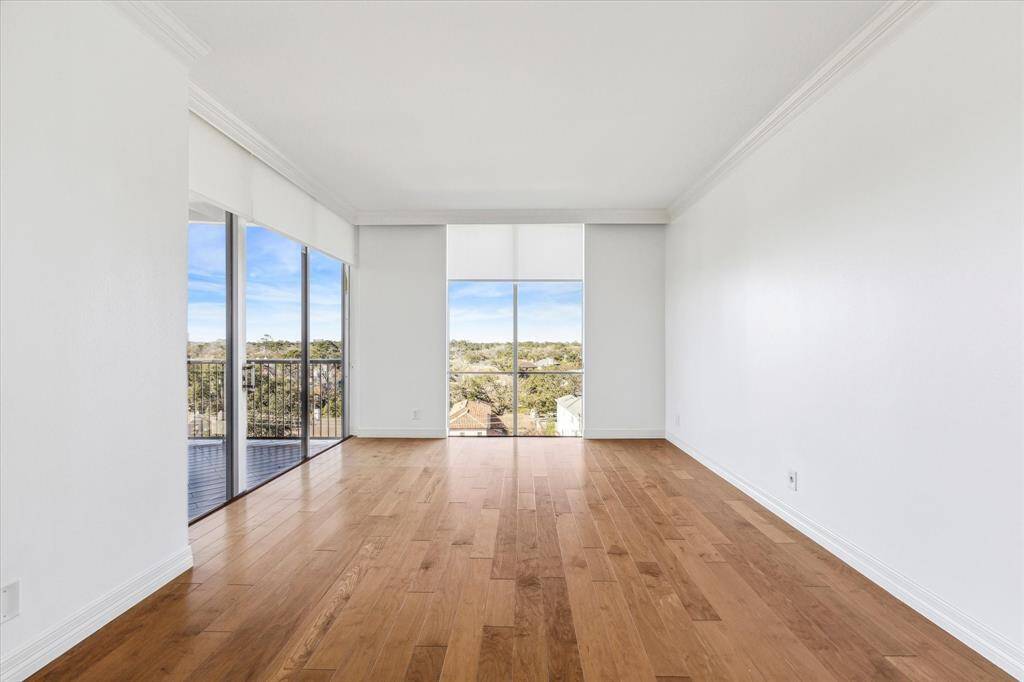 Primary bedroom with hardwood floors, crown molding and shades.