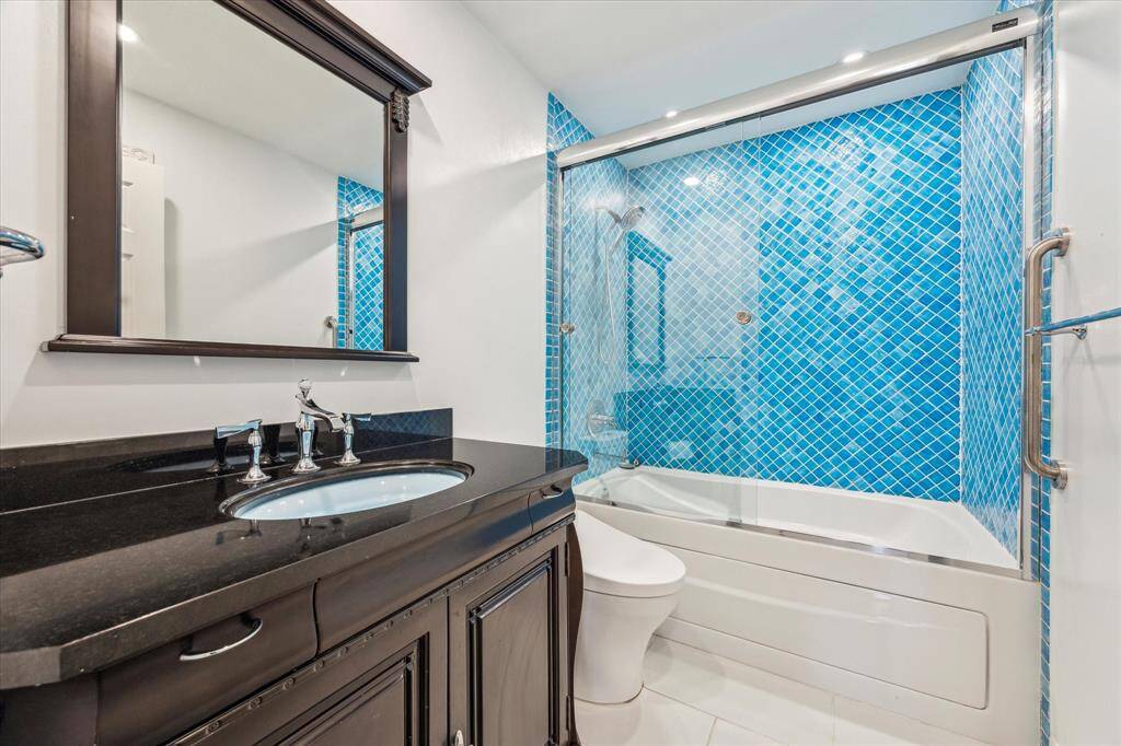 Primary bathroom with tile floors, recessed lighting, jacuzzi tub/shower combo, Toto toilet, and elegant vanity.