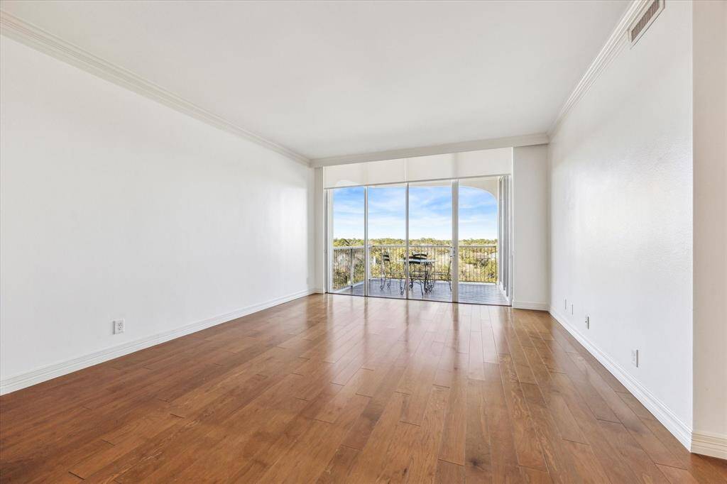 Living room with hardwood floors, crown molding, shades, and balcony access.