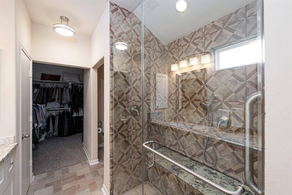 Primary bath with double sinks and walk-in shower with decorative tile