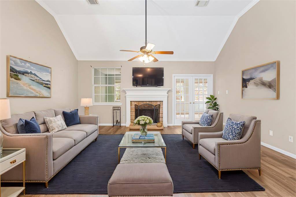 The over sized great room features vaulted ceilings, modern ceiling fan, and cozy fireplace