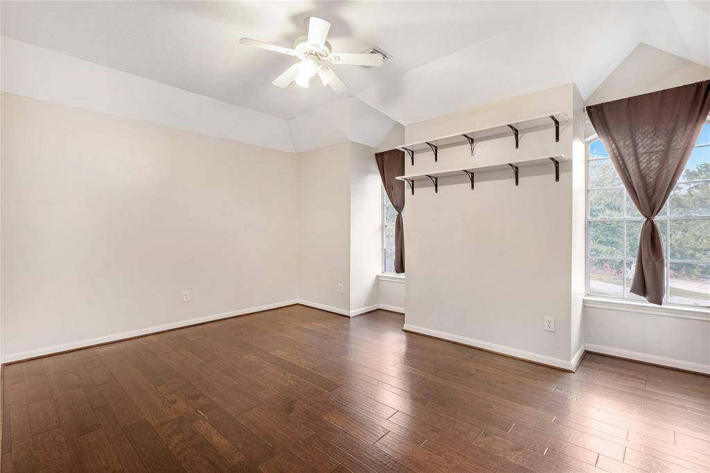 Spacious secondary room with hardwood floors, large windows and a ceiling fan
