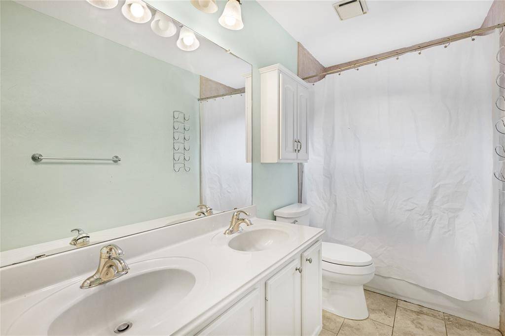 Guest bathroom featuring a dual vanity and full sized tub/shower combo