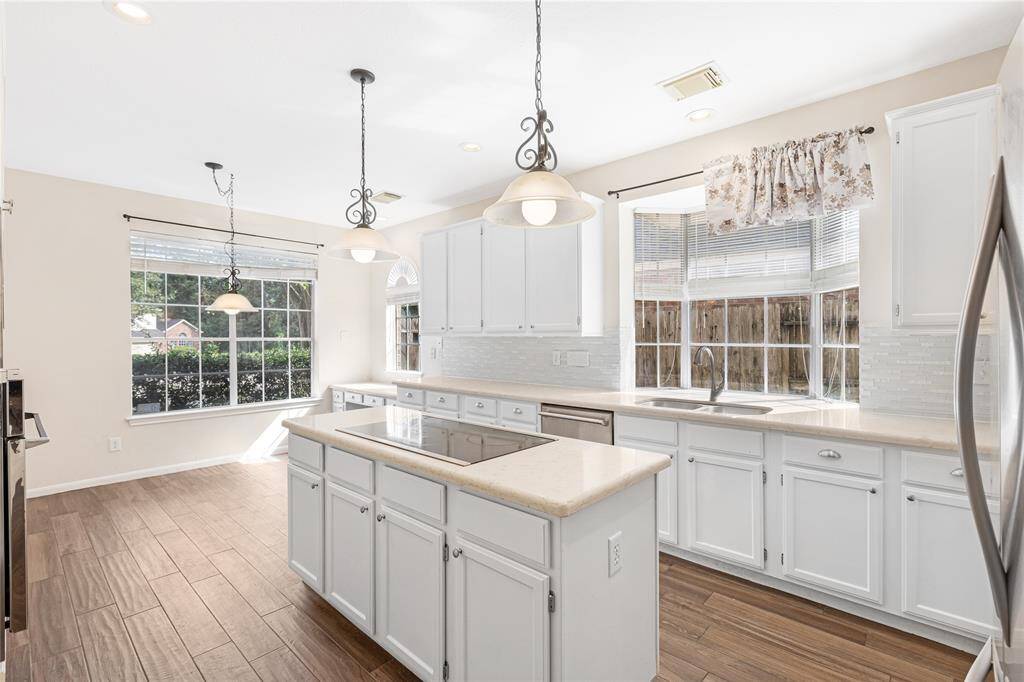 Bright, spacious kitchen with modern white cabinetry, subway tile backsplash, stainless steel appliances, and modern flooring