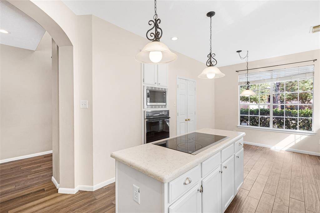 Such a bright, welcoming kitchen featuring modern appliances, a central island with a cooktop, elegant pendant lighting