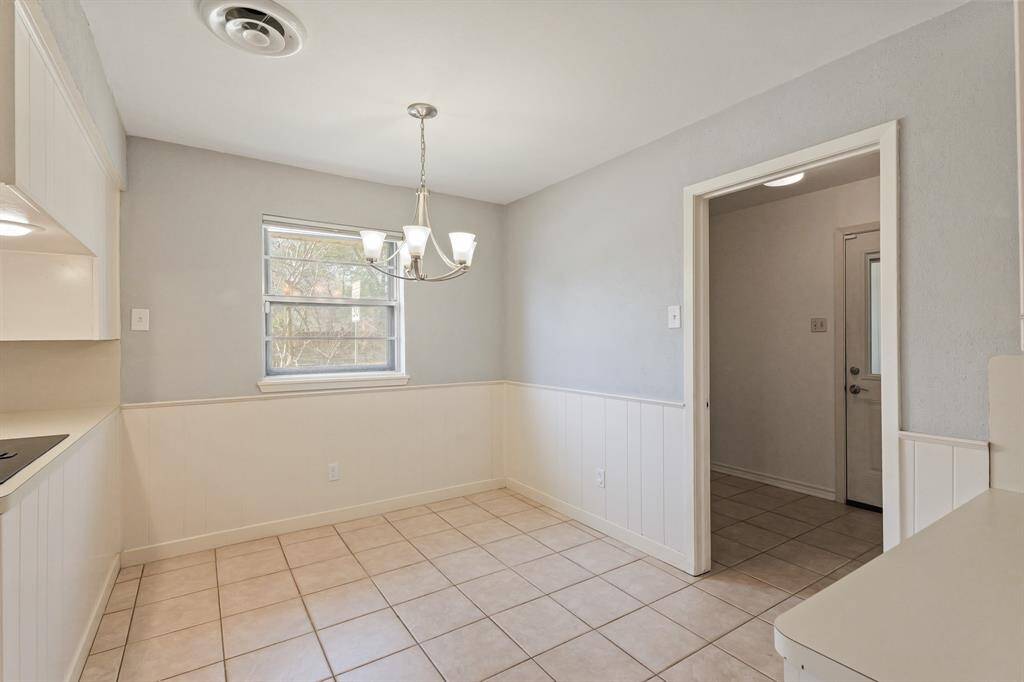 Light and bright breakfast room adjacent to the kitchen with chandelier and access to indoor utility room.