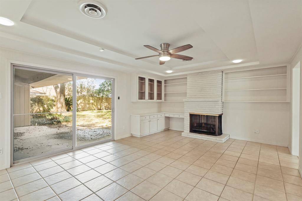 Den with Bright & Airy Living Room with Fireplace! This open-concept living space includes built-in shelving, a cozy fireplace, and recessed lighting.