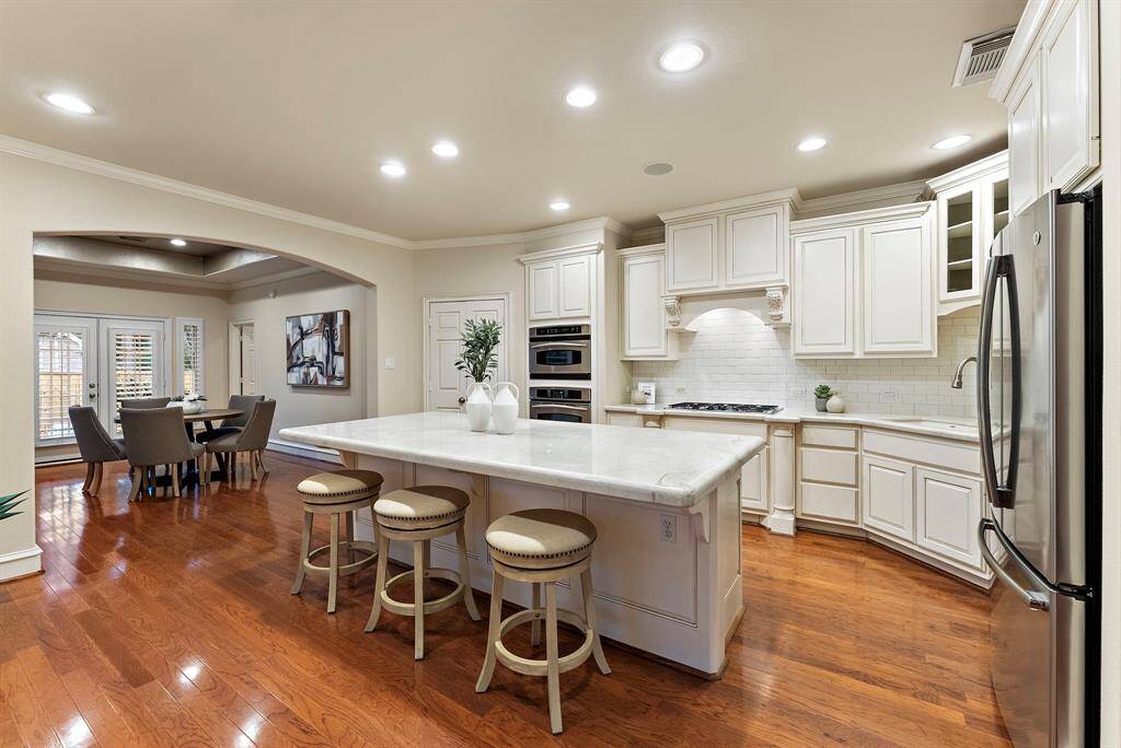 The remodeled kitchen features a spacious oversized island with seating, designed for meal prep and casual dining. Its modern backsplash complements ample cabinetry, while the open layout seamlessly connects to a bright breakfast area, perfect for enjoying morning meals.