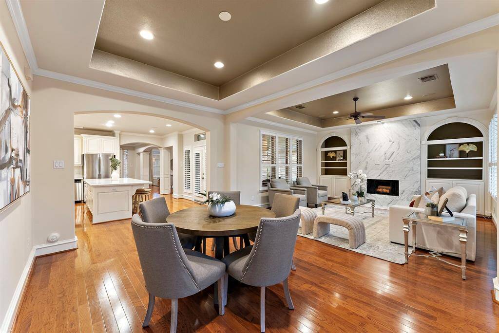 Step into an open-concept living and dining space featuring hardwood floors and tray ceilings. Ideal for both entertaining and everyday comfort, it connects effortlessly to the kitchen.